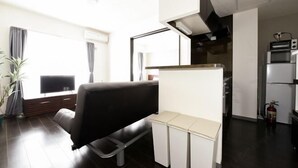 Una sala moderna con sofá, televisión y una cocina equipada.