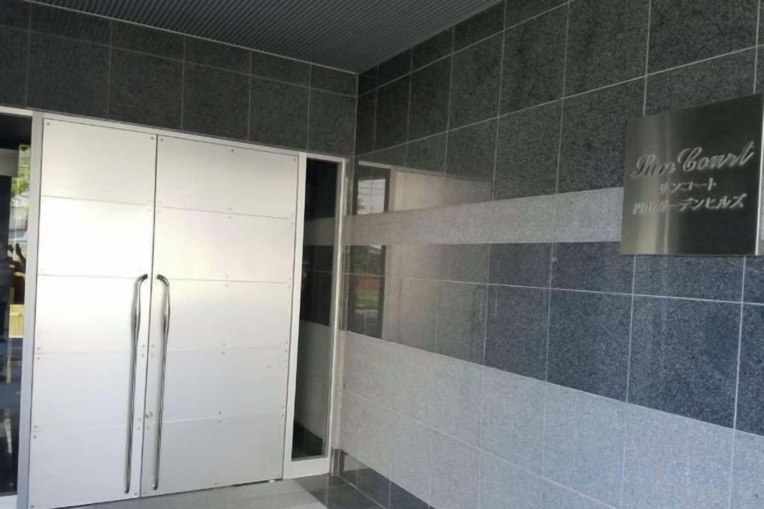 A hallway with a white door, a tiled wall, and a sign with Japanese text.