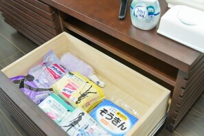 Uma gaveta com diversos itens, incluindo um frasco de loção, um lenço de papel e alguns produtos embalados.
