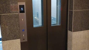 An elevator with a digital display, a wheelchair accessibility button, and a glass panel.