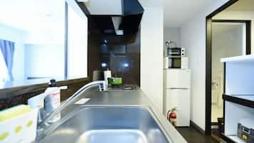 A kitchen with a double sink, a microwave, and a refrigerator.