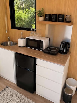 Une cuisine compacte équipée d’un évier, d’un four à micro-ondes, d’un grille-pain, d’une machine à café et d’un petit réfrigérateur.