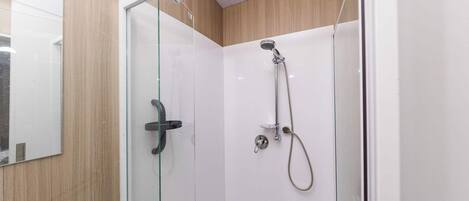 Una cabina doccia in vetro con doccetta e rubinetto a mano.