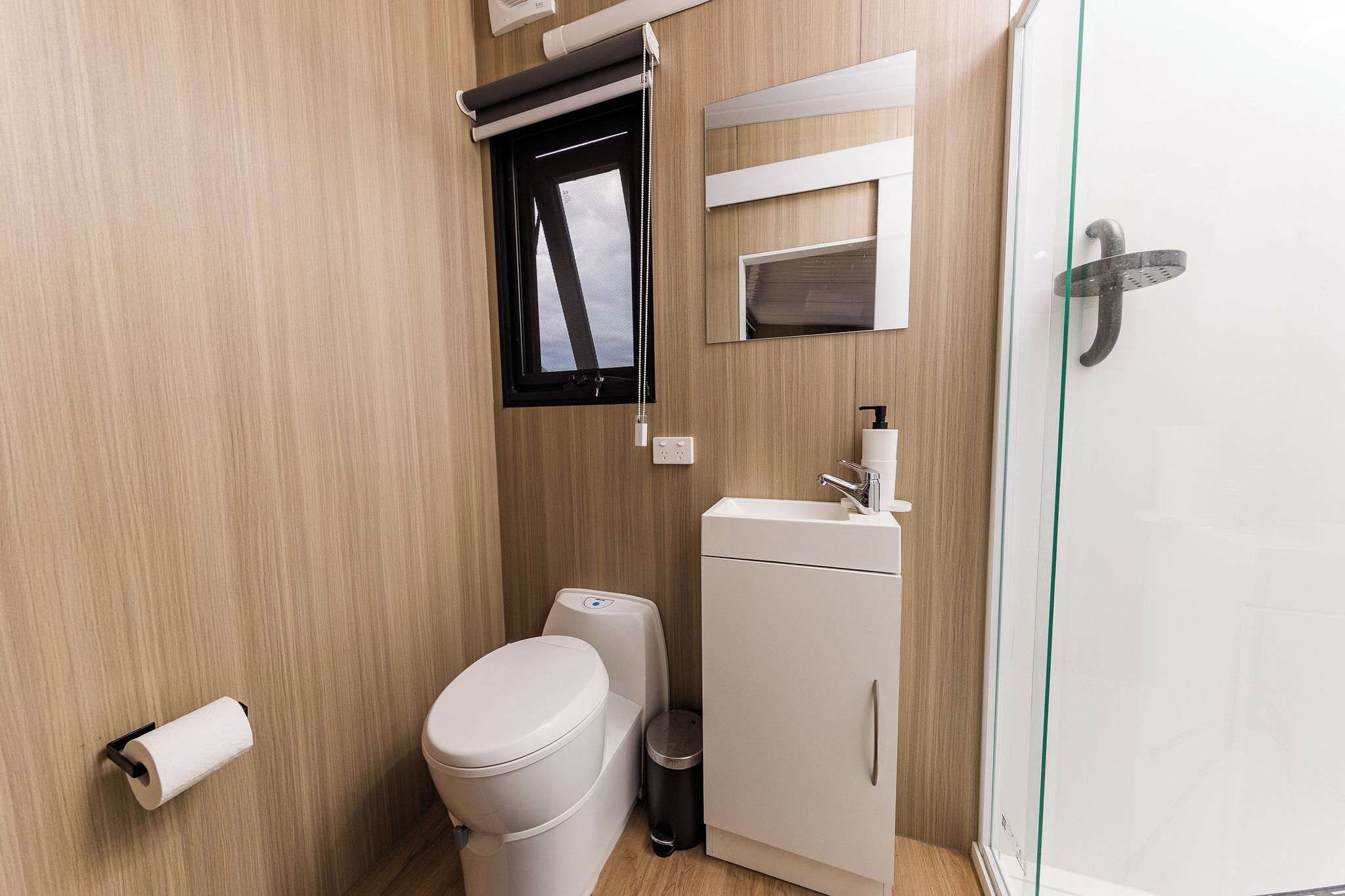 A compact bathroom with a toilet, a small sink, and a shower stall.