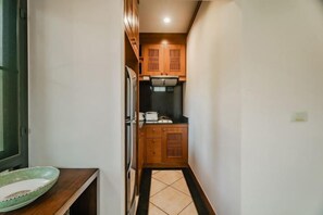 A narrow hallway leading to a kitchen with wooden cabinets and a tiled floor. - Rose Pool Villa, The perfect private oasis (Phuket)
