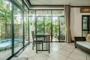 A modern living room with a glass wall, a dining table, and a sofa.