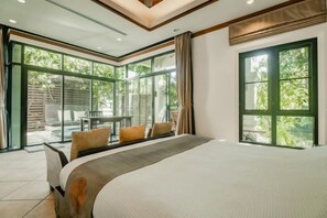 A bedroom with a large bed, a view of a patio with outdoor furniture, and a sliding glass door leading to the outside. - Rose Pool Villa, The perfect private oasis (Phuket)