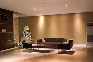 A modern lobby with a sectional sofa, a Christmas tree, and a wall-mounted air conditioning unit.