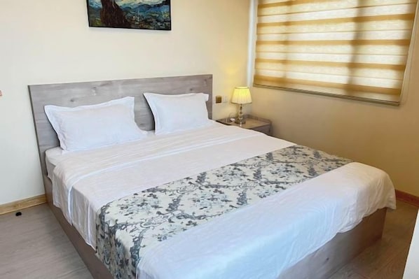 A neatly made bed with a patterned bedspread, a bedside lamp, and a painting on the wall. - Bay View (City of Manila)