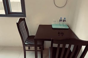 A small dining area with a table and two chairs, a window, and a wall-mounted light fixture. - Bay View (City of Manila)