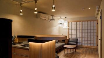 A compact kitchen with a central island, a dining area with a round table, and a traditional sliding door.