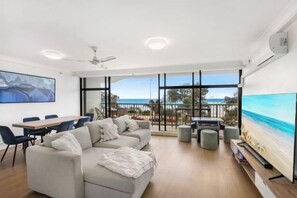 Un salon moderne avec une grande fenêtre, un canapé, une table à manger et un téléviseur.