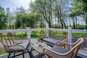 A deck with wicker furniture and a bottle.