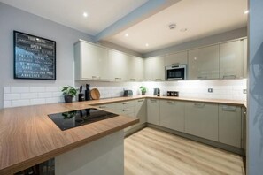 A modern kitchen with a wooden countertop, stainless steel appliances, and light-colored cabinetry.