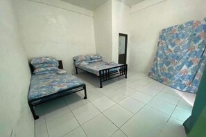 Ein Zimmer mit zwei Betten, einem Spiegel und einem Vorhang.
