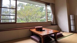 A room with tatami flooring, a wooden table with a bowl, and a window with a view of trees.