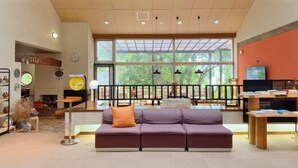 A spacious lobby with a large window, a sofa, a TV, and a reception desk.