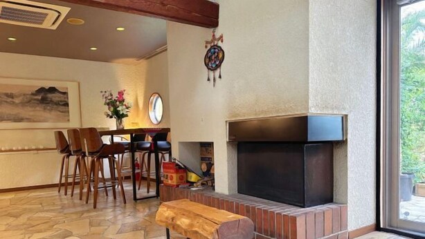 A room with a fireplace, a dining area with chairs, and a bench.