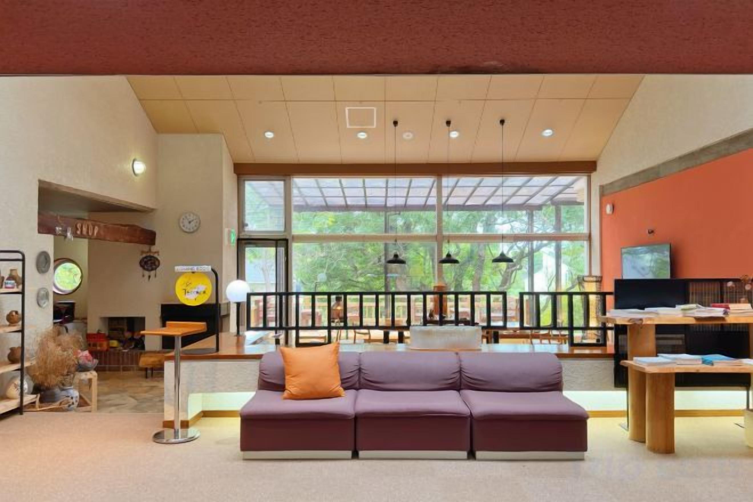 A spacious lobby with a sofa, a television, and a large window.