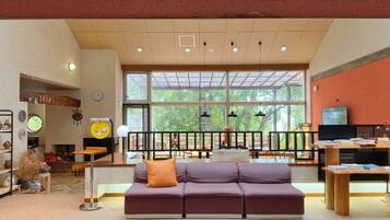 A spacious lobby with a sofa, a television, and a large window.