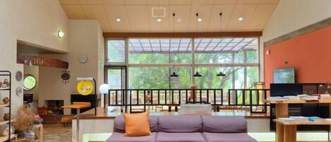 A spacious lobby with a sofa, a television, and a large window.