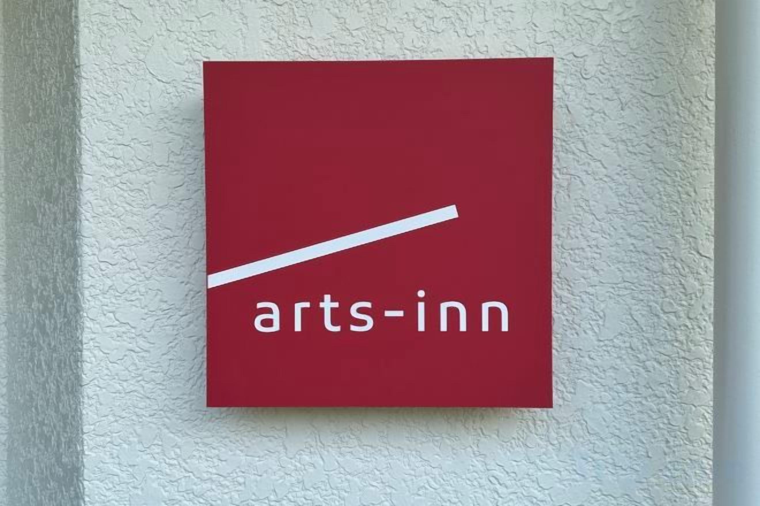 A red sign with the text 'arts-inn' on a textured wall.