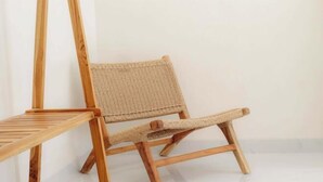 A wooden chair with a woven seat and backrest, positioned against a plain wall.