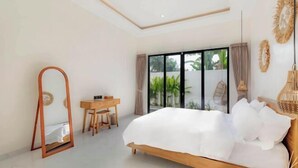 A bedroom with a large bed, a desk, and a mirror.