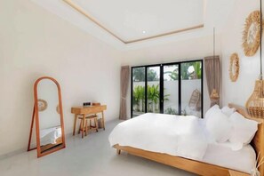 A bedroom with a large bed, a desk, and a mirror. - Villa Sardegna Ubud (Bali)