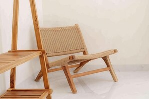 A wooden chair with a woven seat and backrest, positioned against a plain wall. - Villa Sardegna Ubud (Bali)
