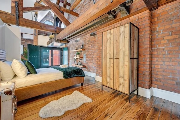 A bedroom with a wooden bed, a brick wall, and a large wardrobe.