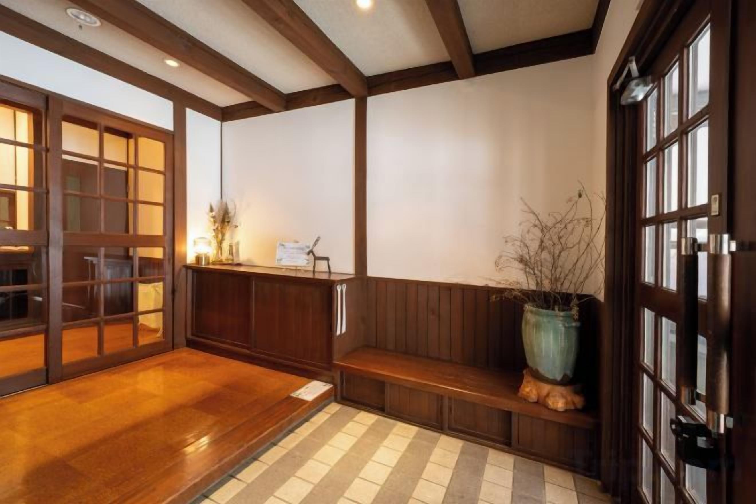 A traditional Japanese interior with tatami flooring, a wooden reception desk, and a large window.