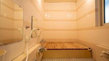 Un baño con una bañera de madera, un espejo y piso de baldosas.