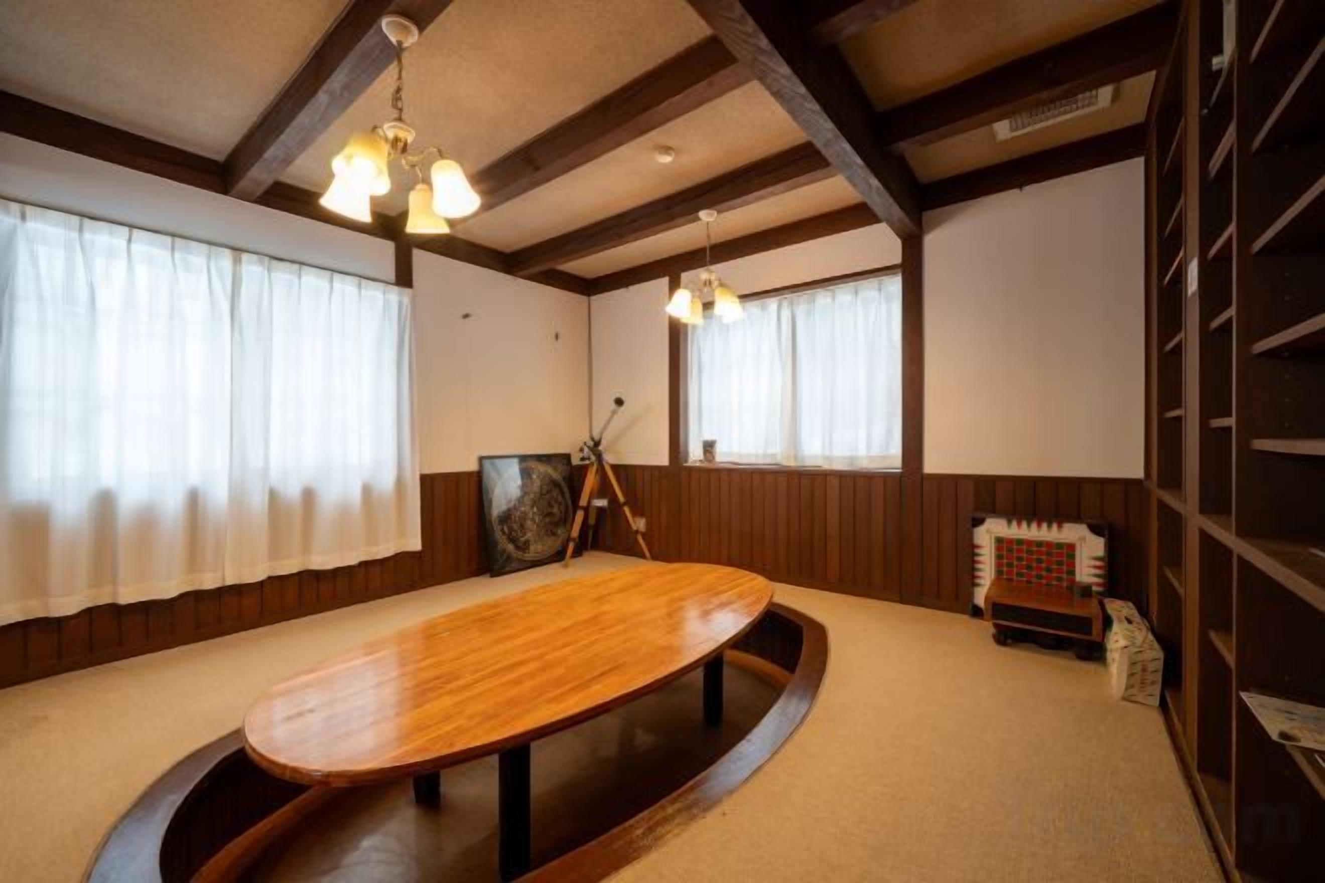 A traditional Japanese-style room with tatami flooring, a low wooden table, and a ceiling with exposed beams.