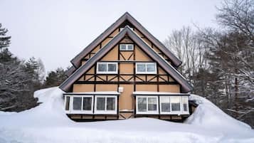 A two-story chalet with a steeply pitched roof, multiple windows, and a snow-covered ground.