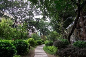 A pathway surrounded by lush greenery and trees, leading to a building with classical architecture. - Shangyuan Hotel Chain (Guangzhou Thirteen Factories Yide Road Metro Station) (Guangzhou)