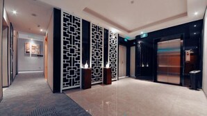 A hotel lobby with a patterned carpet, a reception desk, and a closed elevator. - Shangyuan Hotel Chain (Guangzhou Thirteen Factories Yide Road Metro Station) (Guangzhou)