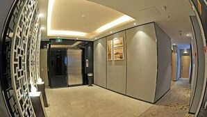 A hotel corridor with a modern design, including a wall-mounted decorative panel, a carpeted floor, and a door leading to an elevator. - Shangyuan Hotel Chain (Guangzhou Thirteen Factories Yide Road Metro Station) (Guangzhou)