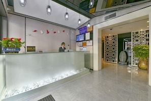 A reception area with a glass counter, a receptionist, and a reception desk.