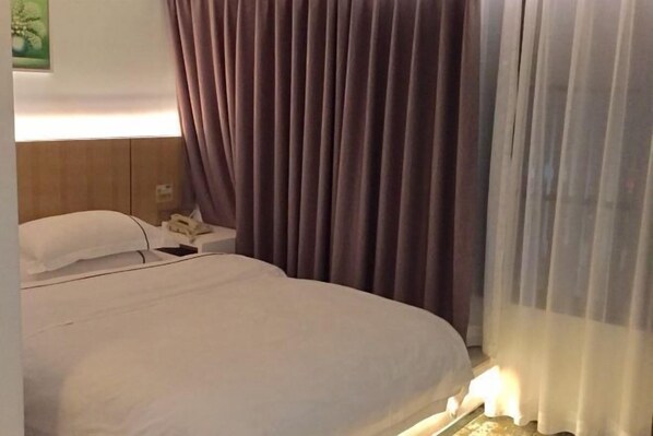 A hotel room with a bed, a bedside table, and a lamp.