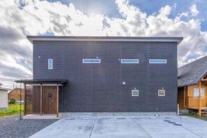 A modern building with a dark facade, rectangular windows, and a covered entrance. - PEACE OF REST TAKASHIMA (Takashima)