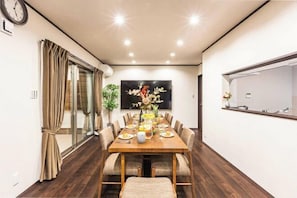 A dining area with a wooden table, chairs, and a vase of flowers. - PEACE OF REST TAKASHIMA (Takashima)