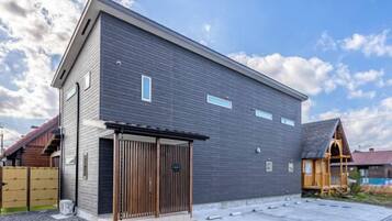 Een modern gebouw met een plat dak, een grote garagedeur en een houten hek op de achtergrond.