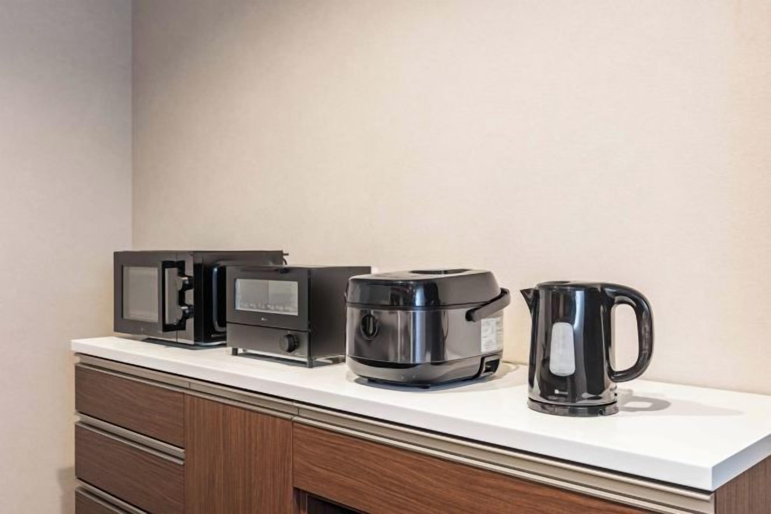 A kitchen counter with a microwave, coffee maker, and kettle.