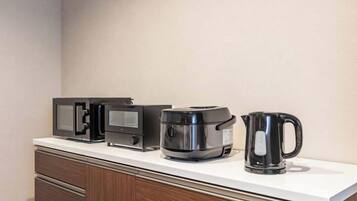 A kitchen counter with a microwave, coffee maker, and kettle.