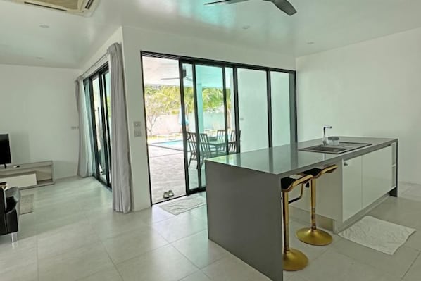 Una cocina moderna con una isla grande, puertas de cristal correderas a un patio y un televisor de pantalla plana.