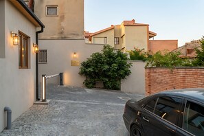 A residential street with a paved driveway, a car parked on the right, and a building with a gated entrance. - MM Hotel Old Tbilisi (Tbilisi)