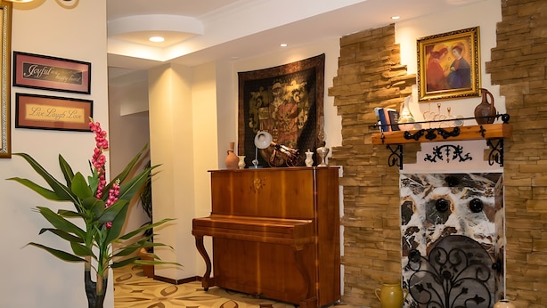 Una habitación con un piano, chimenea y un cuadro grande en la pared.