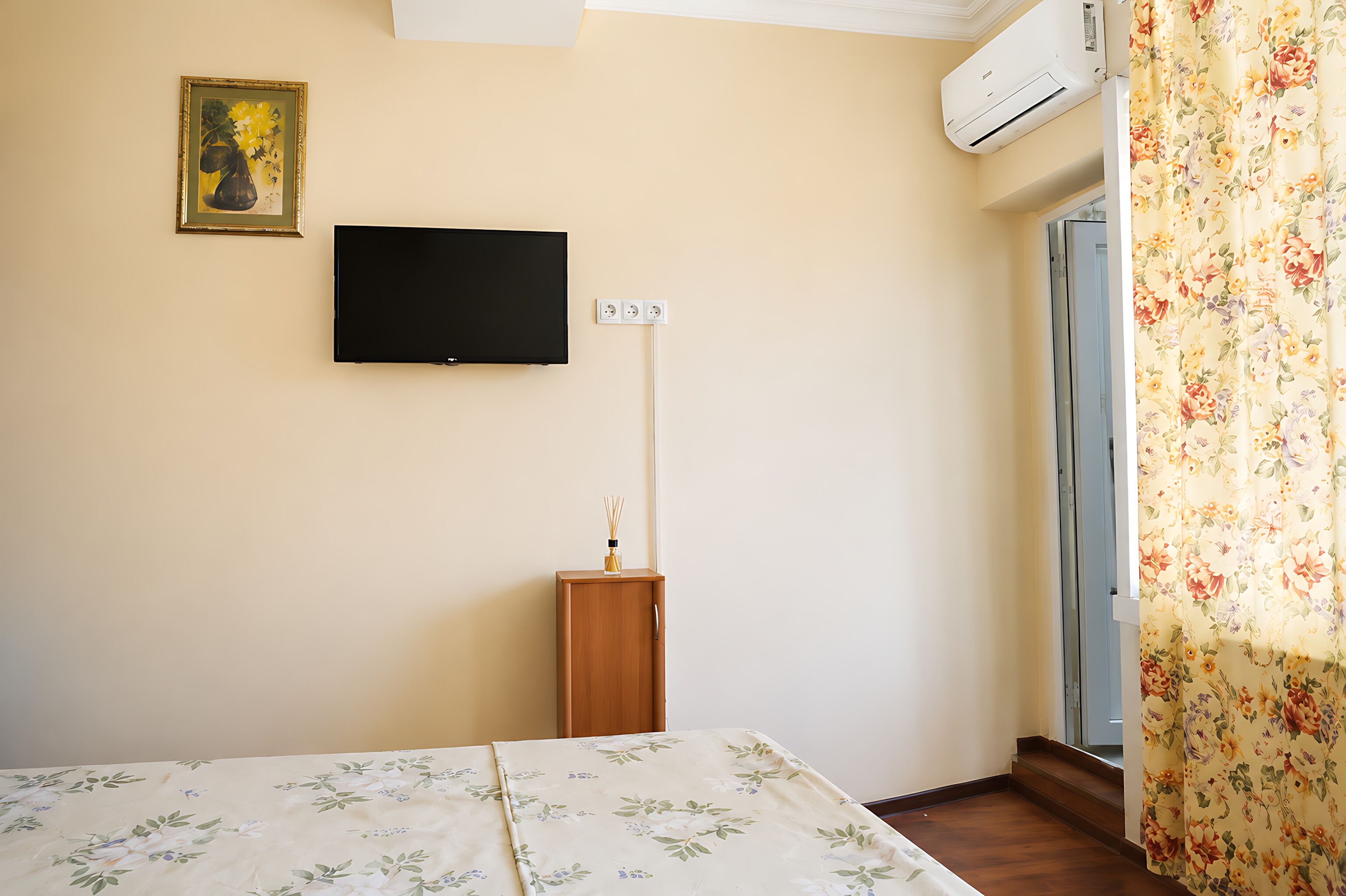 Un dormitorio con cama, televisor, un mueble pequeño y equipo de aire acondicionado.