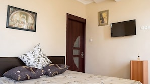 Un dormitorio con cama, dos almohadas, televisor y puerta.